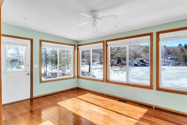 unfurnished sunroom with ceiling fan