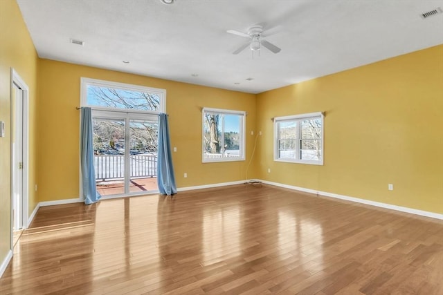 empty room with ceiling fan, light wood-type flooring, and a healthy amount of sunlight