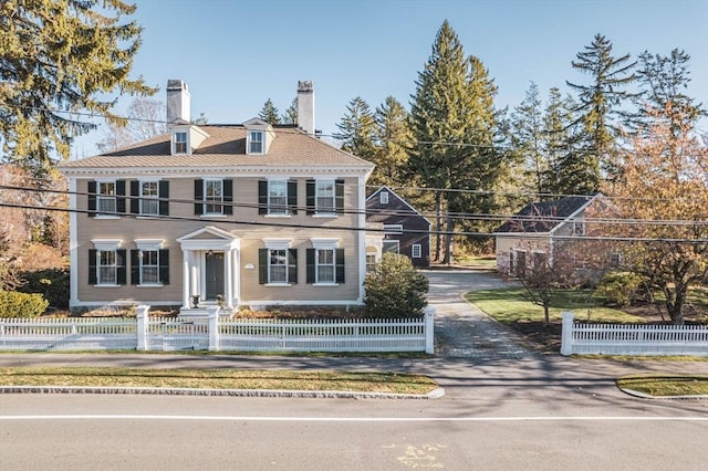 colonial house with a fenced front yard and a chimney