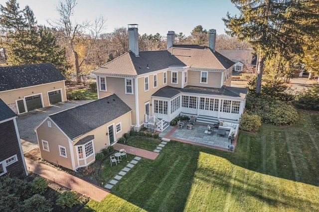 rear view of house with entry steps, a sunroom, a yard, a garage, and a patio