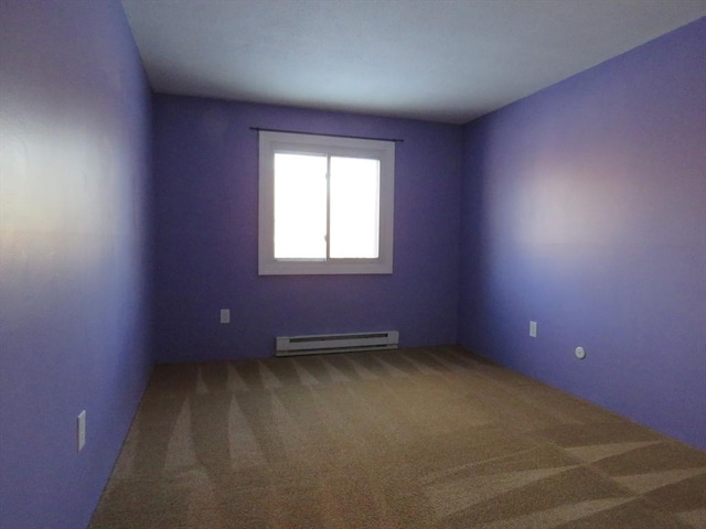 spare room featuring baseboard heating and carpet