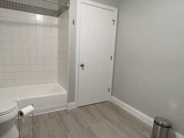 bathroom featuring hardwood / wood-style flooring, tiled shower / bath combo, and toilet