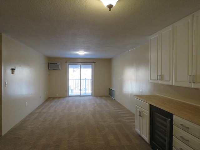 interior space with a wall mounted AC, wine cooler, and a textured ceiling