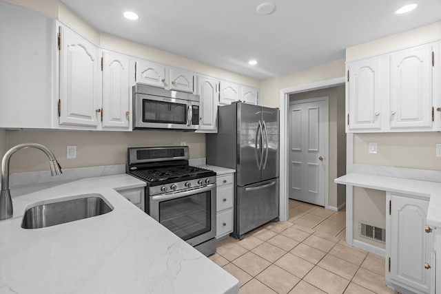kitchen featuring appliances with stainless steel finishes, a sink, white cabinets, light tile patterned floors, and recessed lighting