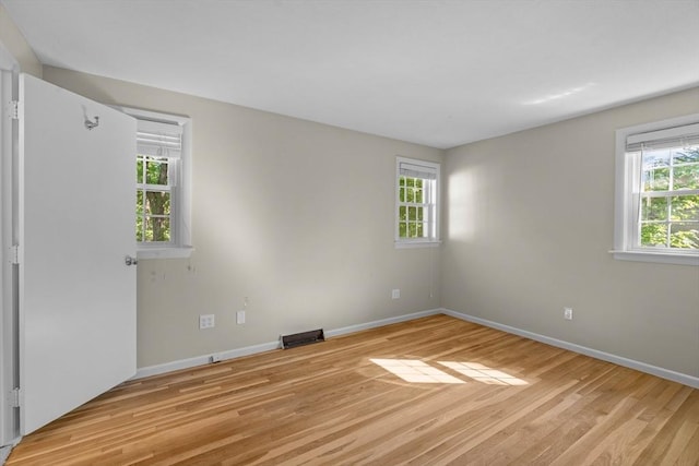 empty room with light wood-style floors, healthy amount of natural light, and baseboards