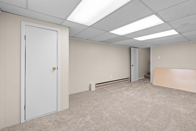 finished basement featuring a baseboard radiator, carpet, and a paneled ceiling
