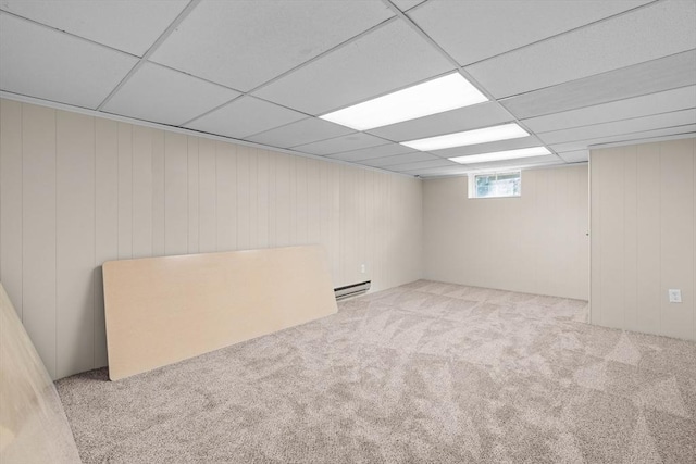 below grade area featuring a baseboard radiator, carpet floors, a drop ceiling, and wood walls