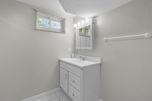 bathroom with baseboards, marble look tiles, vanity, and healthy amount of natural light
