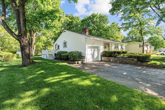 ranch-style home with a chimney, an attached garage, driveway, a front yard, and a wooden deck