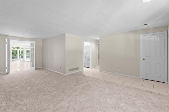 unfurnished room featuring light colored carpet, baseboards, light tile patterned floors, and a textured ceiling