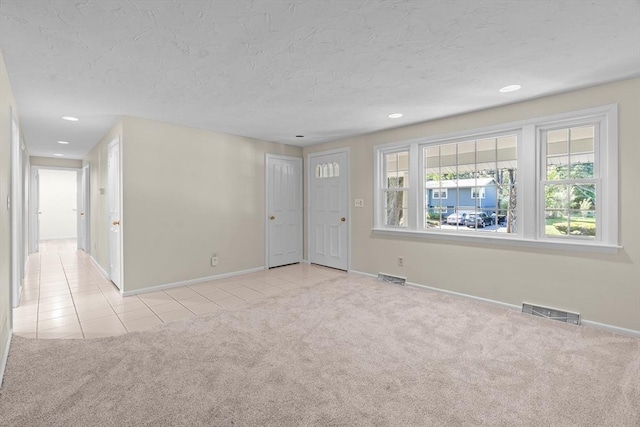 carpeted empty room with tile patterned flooring, baseboards, recessed lighting, and a textured ceiling