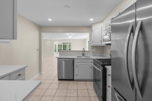 kitchen featuring stainless steel appliances, a sink, light countertops, light tile patterned flooring, and a peninsula