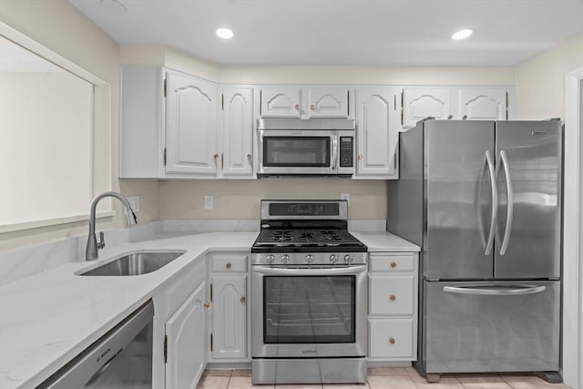 kitchen with stainless steel appliances, a sink, white cabinetry, recessed lighting, and light tile patterned floors