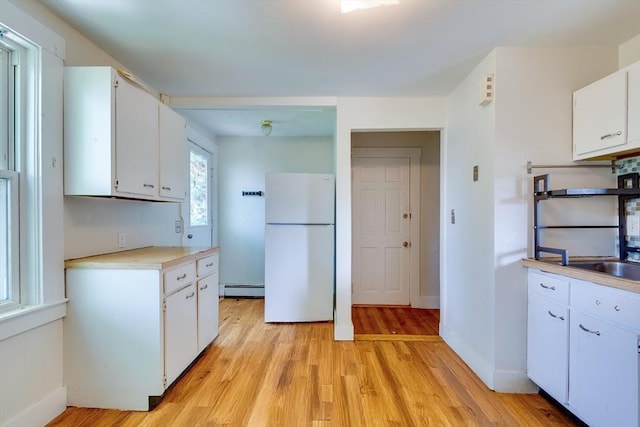 25-29 Chapel St, Norwood, MA 02062 - kitchen featuring freestanding refrigerator, a baseboard radiator, light countertops, white cabinetry, and light wood-style flooring