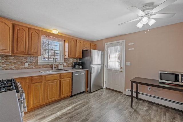 kitchen with appliances with stainless steel finishes, tasteful backsplash, a baseboard radiator, sink, and light hardwood / wood-style floors