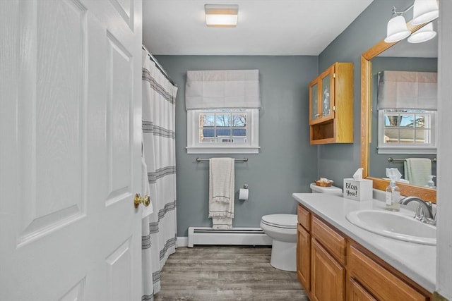 bathroom featuring vanity, a baseboard heating unit, hardwood / wood-style floors, and toilet