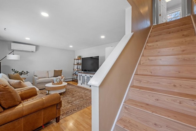 living room with light hardwood / wood-style floors and an AC wall unit