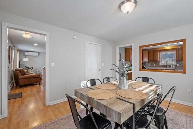 dining area featuring a baseboard heating unit, a wall mounted AC, and light wood-type flooring