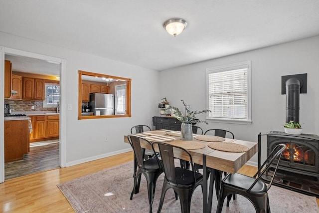 dining space featuring sink, light hardwood / wood-style flooring, and a wood stove