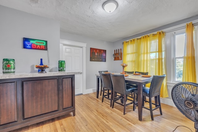 dining space featuring a textured ceiling and light wood-type flooring