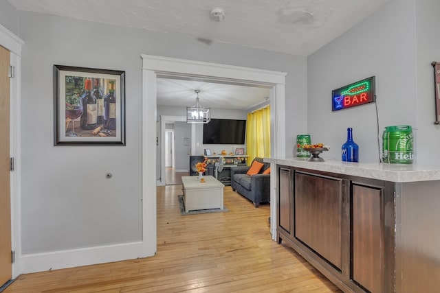 interior space featuring light hardwood / wood-style flooring, a chandelier, dark brown cabinetry, and decorative light fixtures