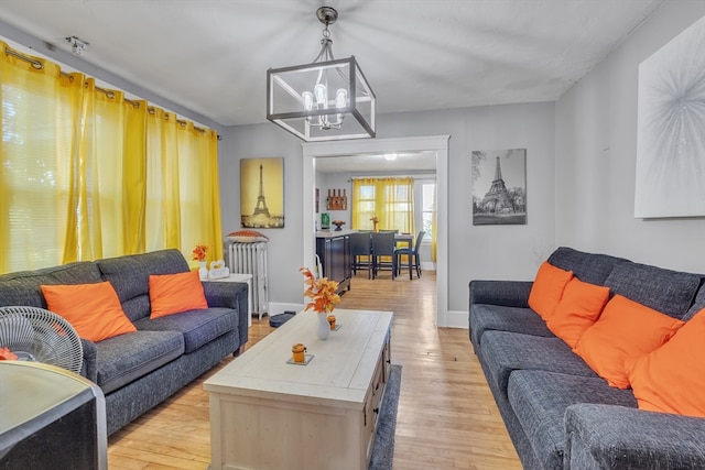 living room with light hardwood / wood-style floors, radiator, and a notable chandelier