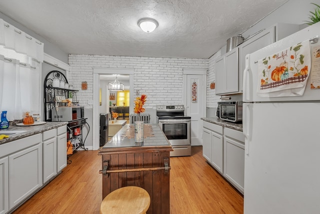 kitchen with light hardwood / wood-style flooring, electric stove, brick wall, and white fridge