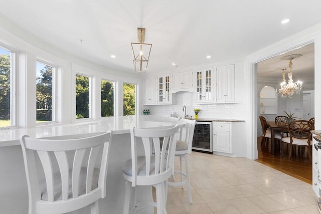 interior space with beverage cooler, hanging light fixtures, backsplash, and a healthy amount of sunlight