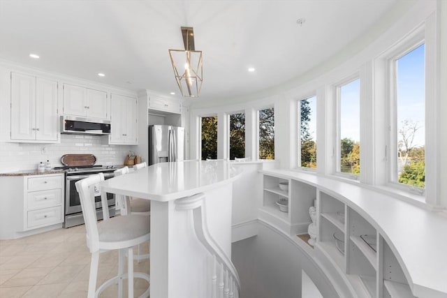 kitchen with stainless steel appliances, white cabinets, light countertops, backsplash, and decorative light fixtures