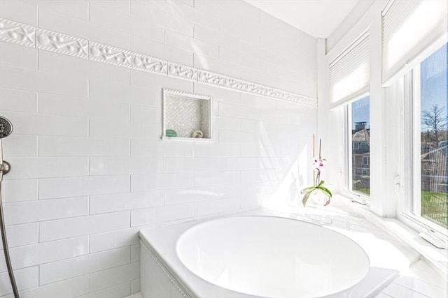 bathroom with a garden tub and tile walls