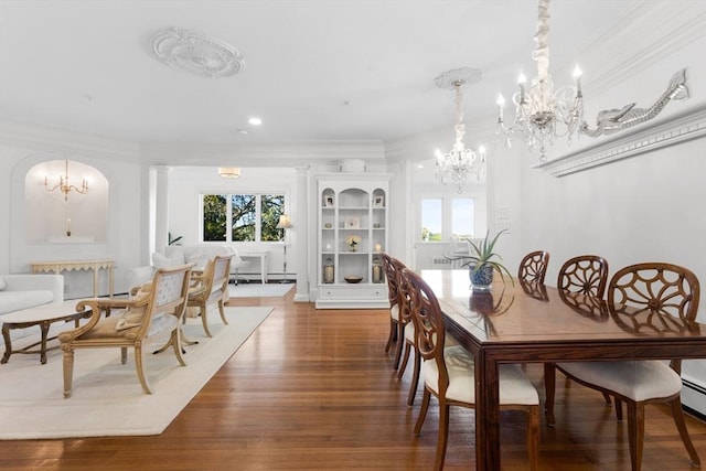 dining space with crown molding, plenty of natural light, wood finished floors, and an inviting chandelier