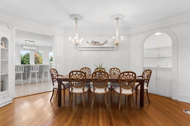 dining space featuring built in shelves, an inviting chandelier, and wood finished floors