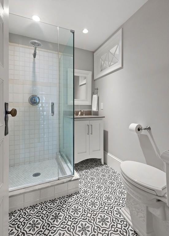 bathroom with baseboards, toilet, a stall shower, tile patterned floors, and vanity
