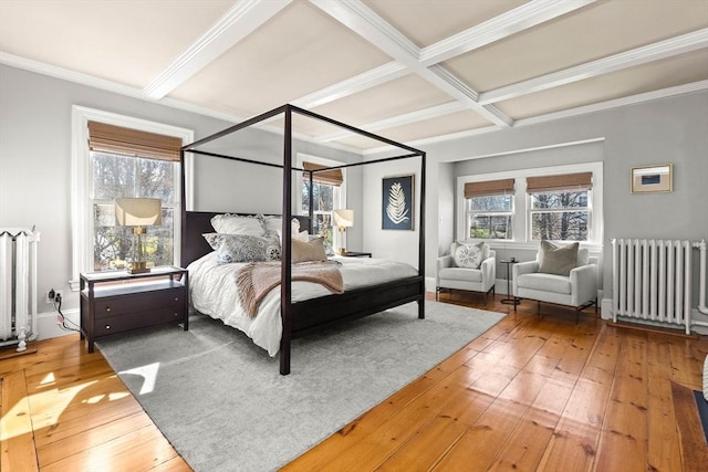 bedroom featuring beamed ceiling, coffered ceiling, radiator heating unit, and hardwood / wood-style flooring