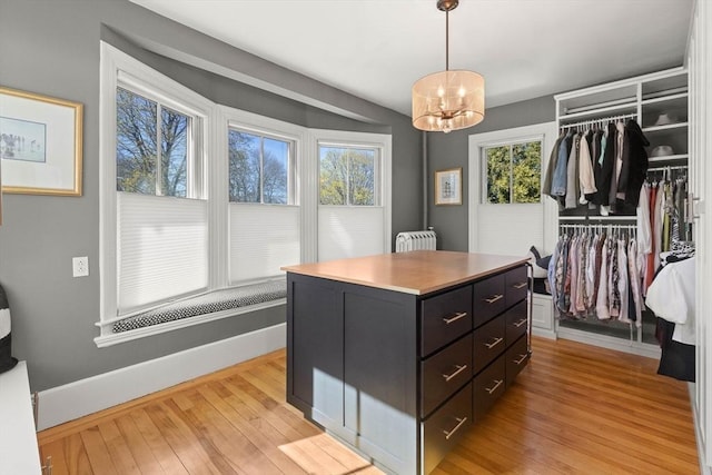 walk in closet featuring light wood-style floors and an inviting chandelier