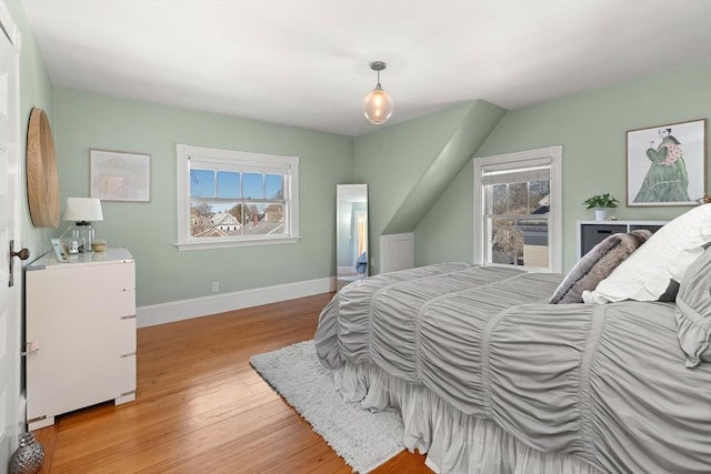 bedroom with light wood finished floors, multiple windows, and baseboards