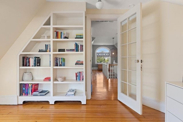 hallway with visible vents, built in shelves, baseboards, hardwood / wood-style floors, and french doors