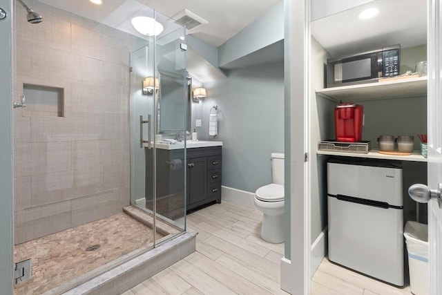 bathroom featuring vanity, baseboards, wood tiled floor, a shower stall, and toilet