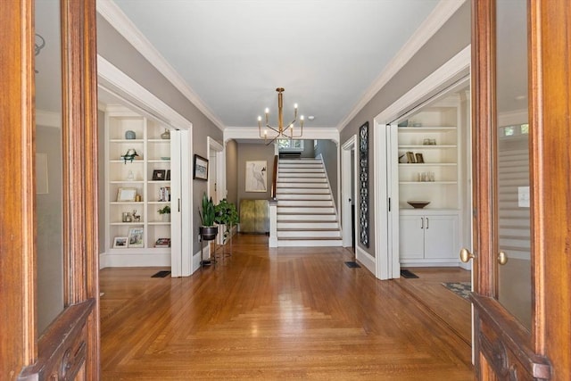 unfurnished dining area with built in features, baseboards, an inviting chandelier, stairs, and crown molding