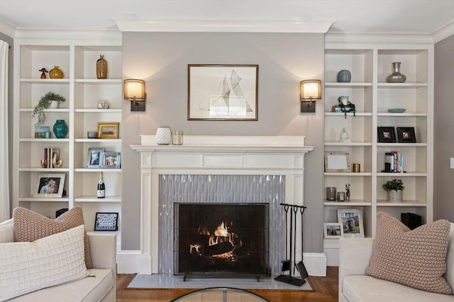living room featuring a high end fireplace, built in features, crown molding, and wood finished floors