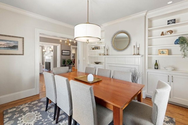 dining area with built in shelves, baseboards, wood finished floors, and ornamental molding