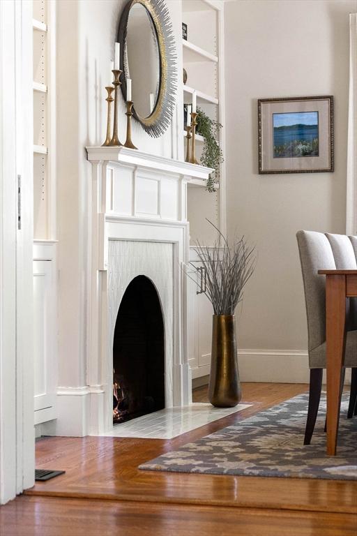 living area with baseboards, a brick fireplace, and wood finished floors