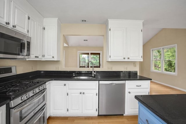 kitchen with a sink, stainless steel appliances, light wood-type flooring, and white cabinetry