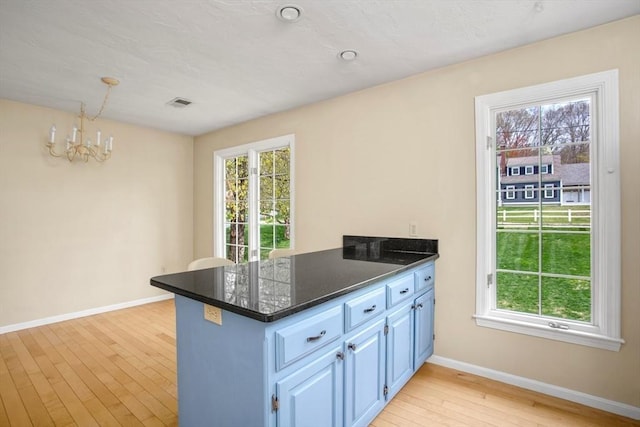 kitchen featuring a notable chandelier, blue cabinetry, light wood-style flooring, a peninsula, and baseboards