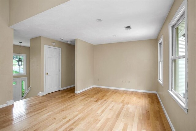 empty room with light wood-style floors, baseboards, and visible vents