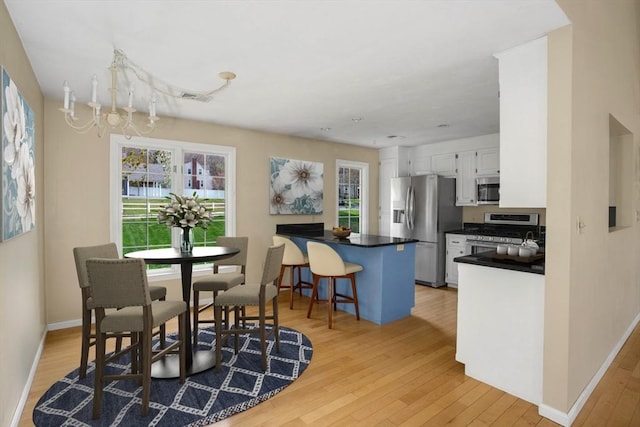 dining space featuring a notable chandelier, baseboards, visible vents, and light wood finished floors
