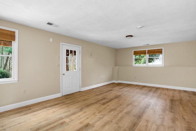 unfurnished room with baseboards, wood finished floors, and visible vents