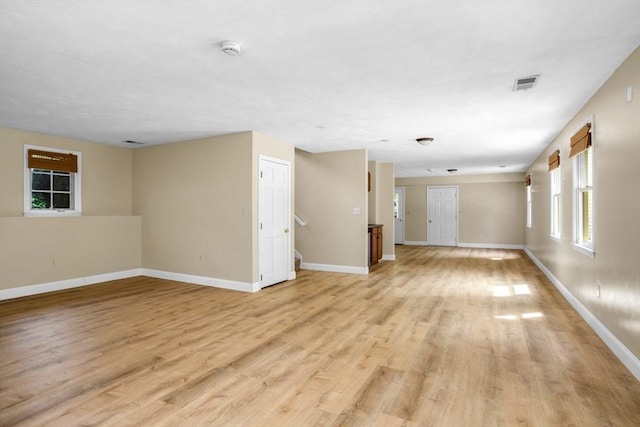 unfurnished living room featuring visible vents, light wood-style flooring, and baseboards