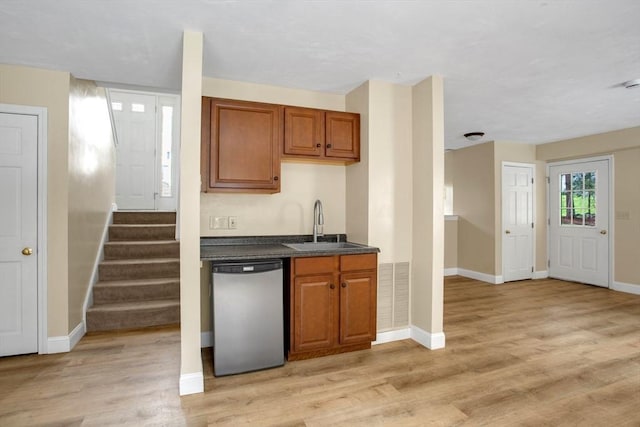 kitchen featuring visible vents, brown cabinetry, baseboards, a sink, and dishwasher