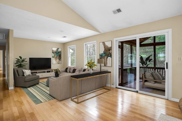 living area featuring visible vents, a healthy amount of sunlight, lofted ceiling, and light wood-style floors